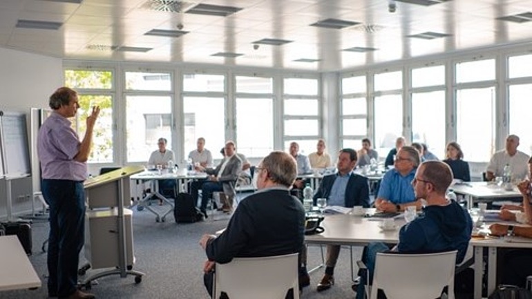 Teilnehmer eines Seminars in einem lichtdurchfluteten Seminarraum.
